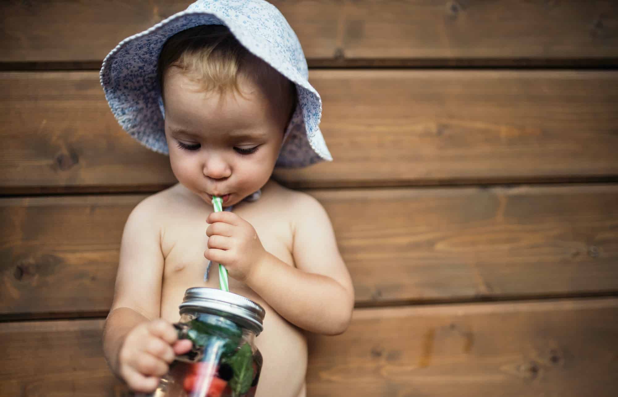 A small girl with a drink outdoors enjoying summer