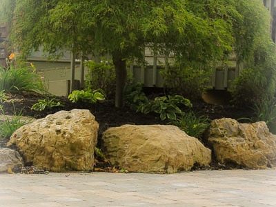 Boulders retain grade change in Backyard landscaping in Greece NY